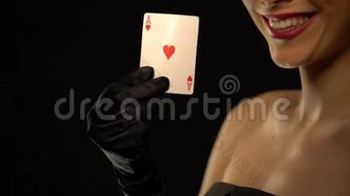 微笑的女人在镜头中展示心灵的王牌，被隔离在黑色的背景上